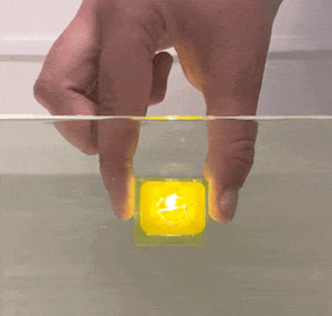 Yellow Alex light up glo cube sensory toy lighting up  when held under water. 